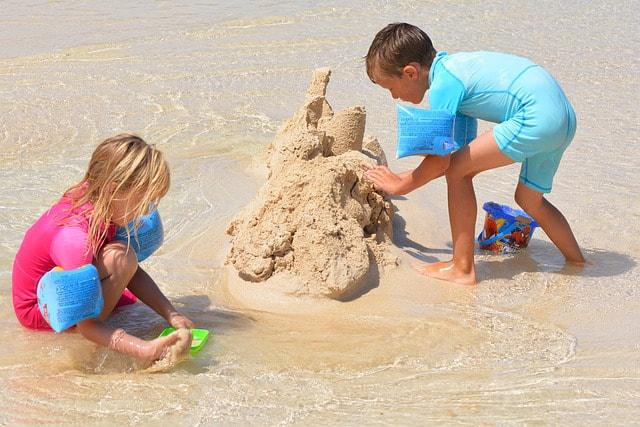 Children playing around five mounds of sand