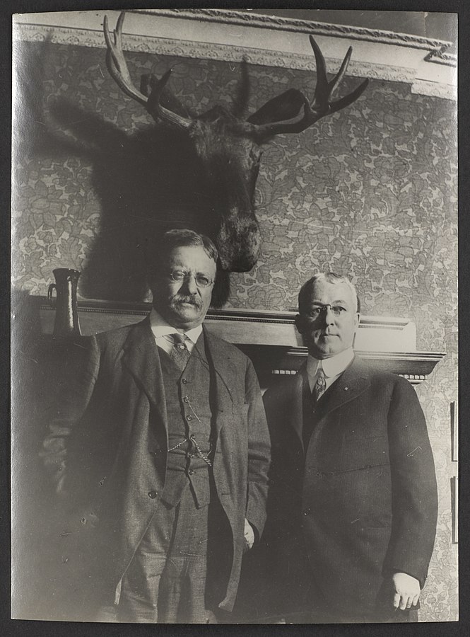 Man formally dressed and a stag with horns